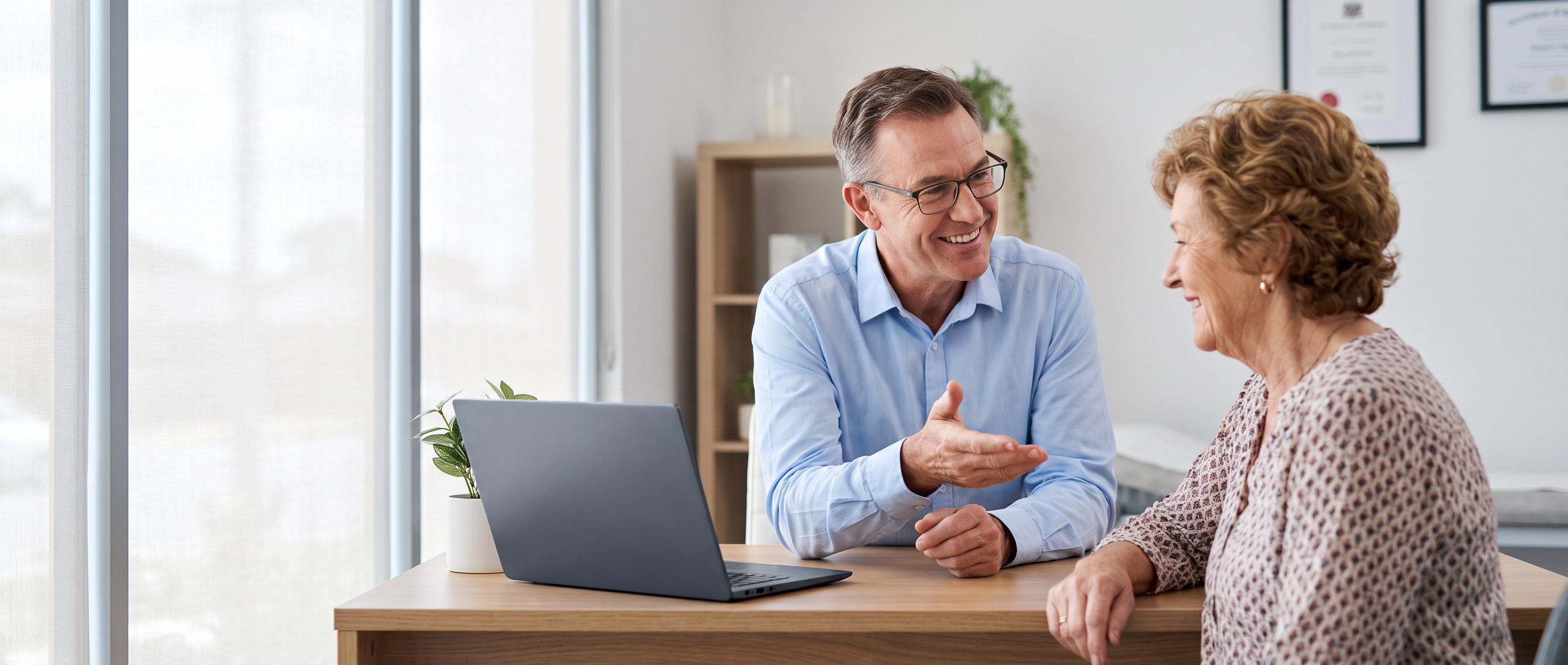 A doctor talking with an older patient across a consulting room desk