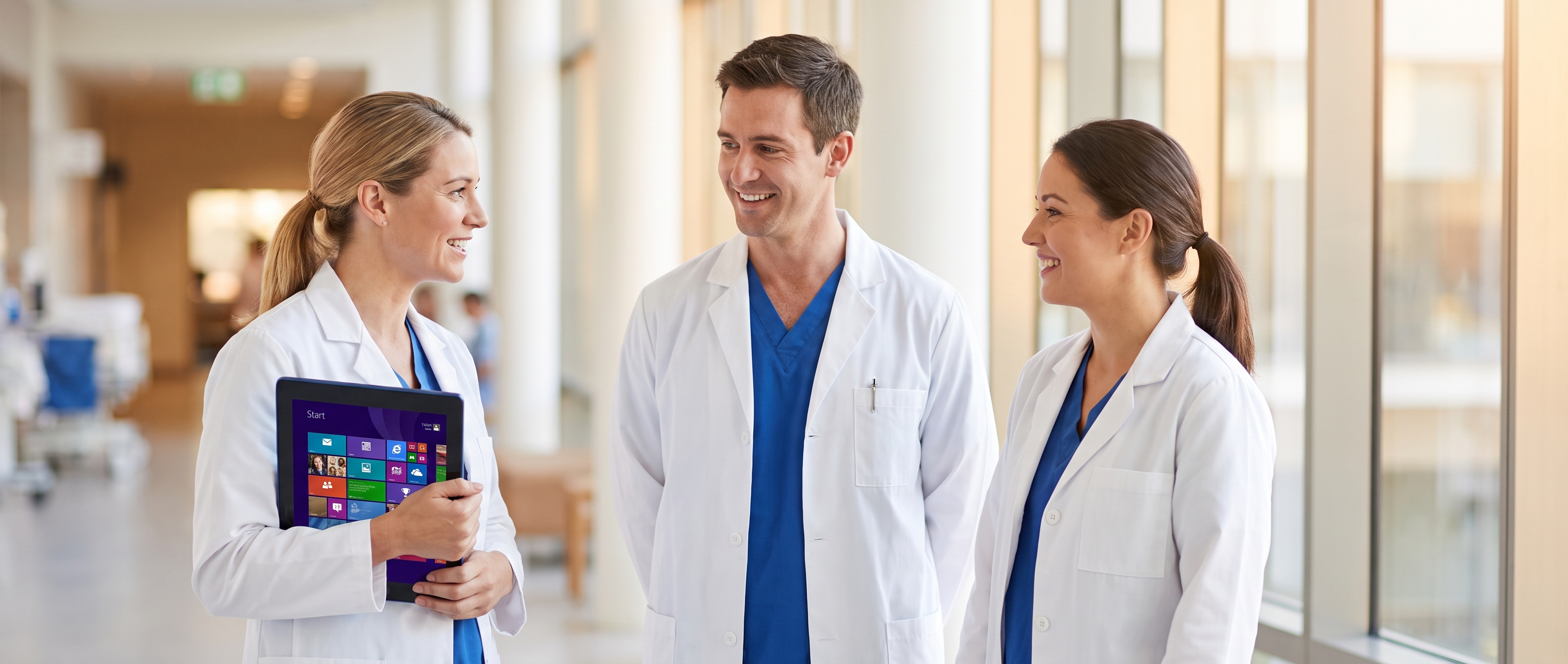 Hospital clinicians discussing a Dragon Medical One deployment in a modern hospital corridor