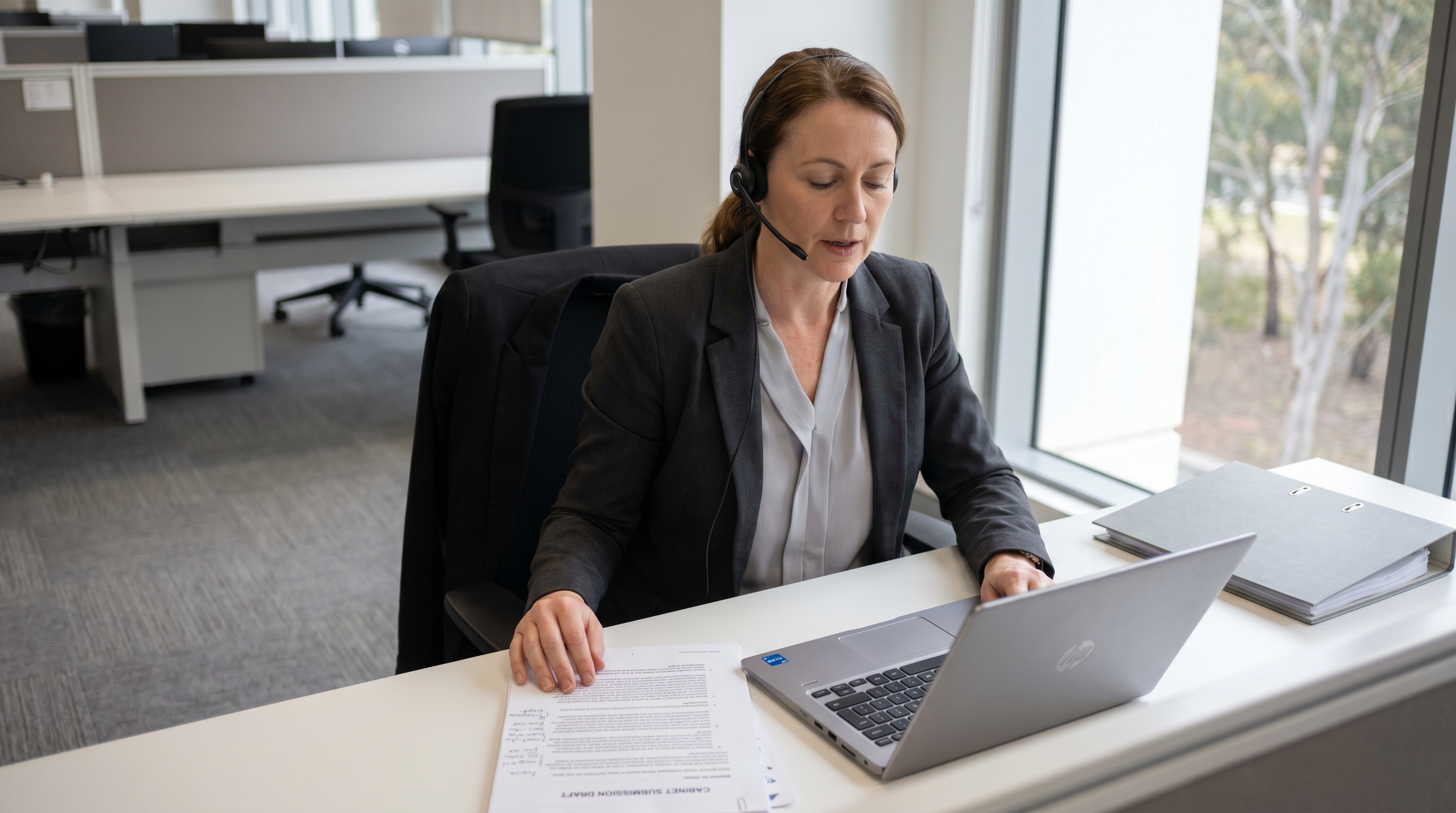 Australian senior policy officer drafting a cabinet briefing at her desk in a Commonwealth department in Canberra